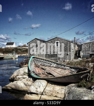 Concha rota de un barco de madera sobre rocas en un pueblo pesquero de Nueva Escocia Foto de stock