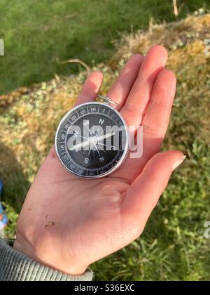 Mano del niño sosteniendo una brújula sobre un fondo negro Fotografía de  stock - Alamy