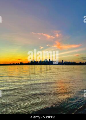 Fecha con el anochecer. Reúnase con el centro de Toronto durante la hora dorada. Puesta de sol sobre el agua, el horizonte y los ecos de la tranquilidad.