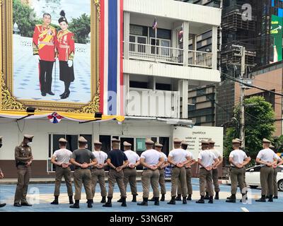 La policía de Tailandia está a la atención y se alinean frente a una gran imagen de cartel del Rey y la Reina de Tailandia. Tailandia, sudeste asiático