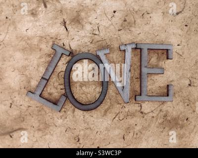 “AMOR” tipografía letras de madera hechos a mano papel textura fondo.