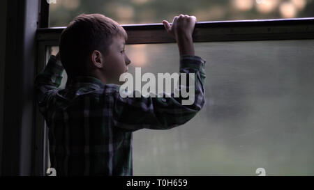 Muchacho feliz es viajar en tren por la noche, mirando por la ventana Foto de stock
