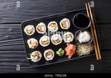 Rollos japonesa uramaki frescos servidos con salsas, jengibre y wasabi closeup en una placa en la tabla superior horizontal vista desde arriba Foto de stock