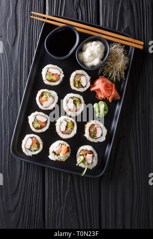 Rollos japonesa uramaki frescos servidos con salsas, jengibre y wasabi closeup sobre un plato en la mesa. Vista superior de la vertical desde arriba Foto de stock
