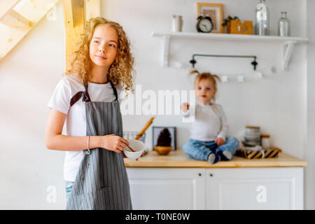 Lindo joven curly chica y su hermana niño preparando el desayuno para los padres y sonriente. El amor familiar y el concepto de cuidado. Foto de stock
