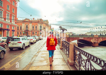 Rubia en una chaqueta roja paseos a lo largo de la orilla del río Fontanka. San Petersburgo, Rusia - 15 de marzo de 2019.