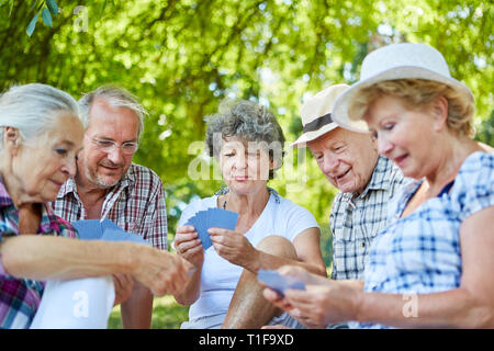 Altos amigos jugando cartas en el parque en verano como un pasatiempo Foto de stock