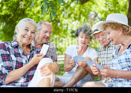 Grupo de Amigos jubilados jugando a las cartas en el parque en verano Foto de stock