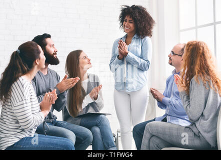 Los jóvenes aplaudiendo a mujer en la reunión del grupo de rehab