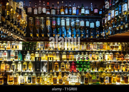 Una amplia selección de whiskys escoceses iluminado en estantes de vidrio y en óptica, Escocia