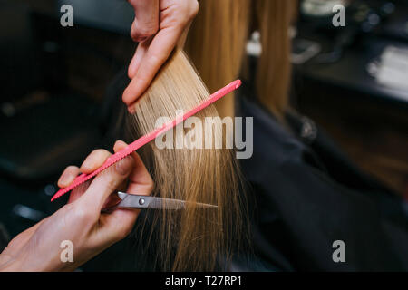 Close-up de peluquero manos peinando el cabello rubio antes de peinado en el salón Foto de stock
