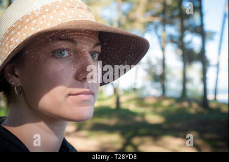 Cerca de una mujer joven con sombrero en el sol.