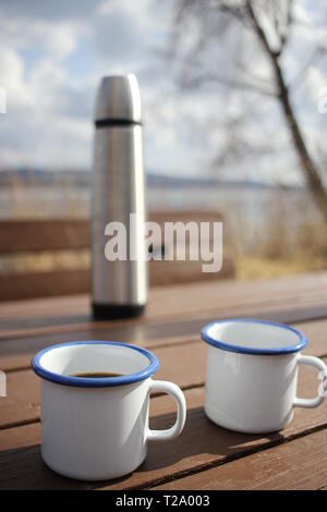 Dos tazas de café y un termo en una mesa de madera Foto de stock