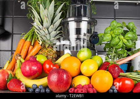 Licuadora lento en la cocina con muchos zumos de frutas y verduras