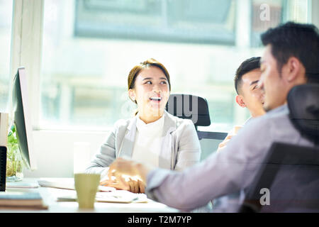 Tres jóvenes empresarios asiáticos reunidos en oficina, feliz y sonriente.