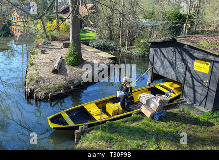 Lehde, Alemania. 04 abr, 2019. Andrea Bunar, postwoman, ha tomado su amarillo barcaza desde un hangar y lo carga con cartas y paquetes. En el Spreewald el correo será entregado de nuevo por el agua en los próximos meses. Hasta el mes de octubre la postwoman Andrea Bunar traerá cartas, postales y paquetes a los habitantes de nuevo. Cada día ella viaja alrededor de ocho kilómetros sobre el agua. Crédito: Patrick Pleul/dpa-Zentralbild/ZB/dpa/Alamy Live News