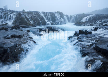 Bruarfoss cascada. El agua es de color turquesa y hermosas cascadas. Atracción turística en Islandia. Niebla matutina Foto de stock