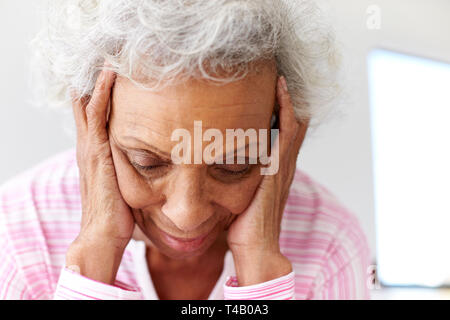 Mujer mirando deprimido infeliz sentado en el lado de la cama, en su casa con la cabeza entre las manos