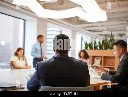Vista posterior de la reunión de profesionales de los negocios en torno a una mesa en la oficina moderna Foto de stock