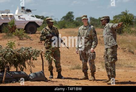 El subteniente Greg Kabusk (centro) y el Subteniente Mike Kassehin, 101º Airborne Div. 2ª Brigada del Ejército de los Estados Unidos, África regionalmente alineados force (RAF), asesores de formación, hablar a través de movimiento de tropas y posicionamiento táctico con un soldado de Zambia durante del ZAMBATT campo V ejercicio de entrenamiento. Del ZAMBATT V, la quinta iteración de tropas del país de Zambia para desplegarse en apoyo de las Naciones Unidas para la misión de estabilización multidimensional en la República Centroafricana (MINUSCA), pasó más de seis semanas de trabajo con EE.UU., Reino Unido, y los socios franceses la capacitación y preparación para su misión al África Central Foto de stock
