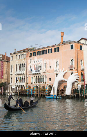 Venecia en góndola en el Gran Canal, Italia y manos gigantescas esculturas 'Soporte' por Lorenzo Quinn en Ca' Sagredo Hotel Foto de stock