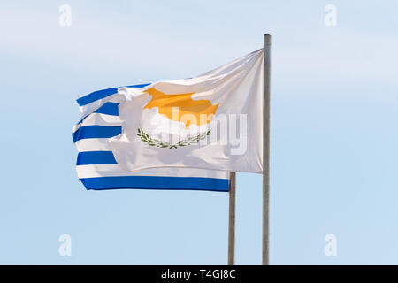 Ondeando banderas griegas y Cipriano agaist el cielo azul en el viento fuerte Foto de stock