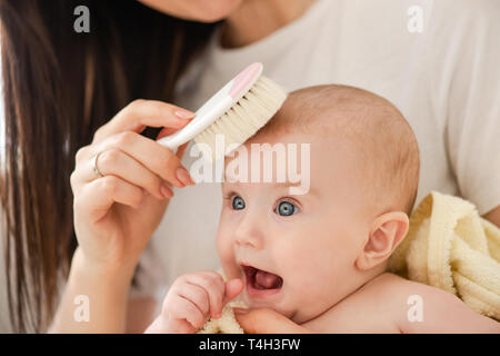 Madre cepillando el cabello de su bebé recién nacido usando un cepillo de  pelo suave para estimular los folículos pilosos del bebé y aumentar el  flujo sanguíneo del cuero cabelludo para un