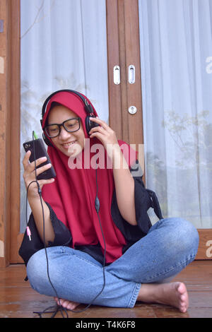 Los adolescentes musulmanes de Asia, con una sonrisa utilizando Teléfonomóvil para escuchar música y selfies para tomar fotografías de ellos Foto de stock