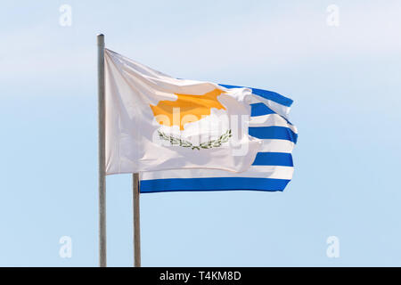 Ondeando banderas griegas y Cipriano agaist el cielo azul en el viento fuerte Foto de stock