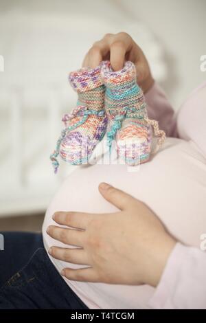 Mujer embarazada con medias tejidas en el vientre del bebé