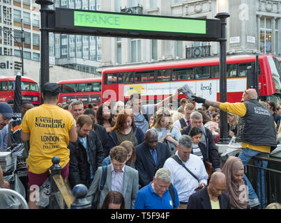 Los proveedores distribuir copias del periódico Evening Standard en hora punta para viajeros se apiñan en la estación de metro de Oxford Circus en Londres Foto de stock