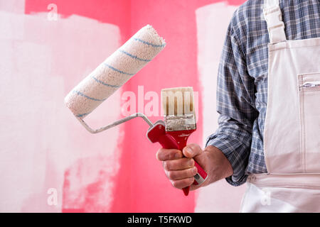 Trabajador Pintor De Casas Caucásicas Con Un Mono De Trabajo Blanco, Con El  Rodillo Pintando La Pared Con Pintura Colorida. Industria De Construccion.  Fotos, retratos, imágenes y fotografía de archivo libres de