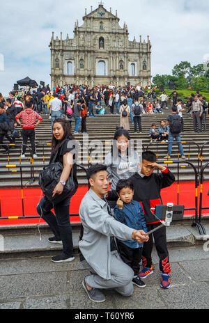 Noviembre 2018 - Macao, China: hombre asiático teniendo una familia selfie delante de las Ruinas de San Pablo en una gran masa de turistas chinos Foto de stock