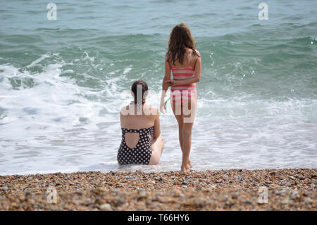 Dos chicas en trajes de baño, en Seaside Beach, mirando hacia el mar azul y blanco shore olas