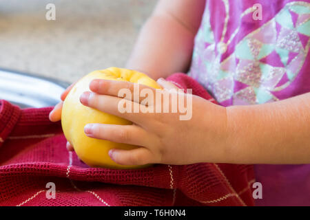 Niña ayudando a la madre hacer membrillo y pegar, aquí ella se sostenía en sus manos después de lavar y secar con un paño rojo. Foto de stock