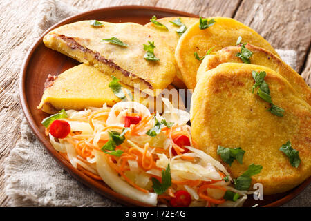 Comida salvadoreña Pupusas frito servido con coleslaw cerca en una placa horizontal sobre la mesa.