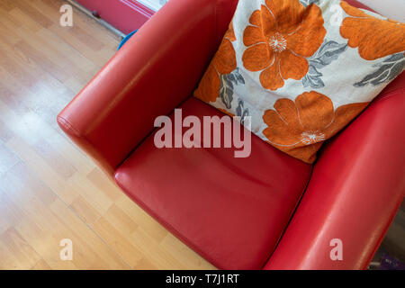Mirando hacia abajo en un cómodo sillón rojo con un cojín floral. Foto de stock