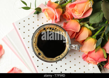 Composición con una taza de café, cuadernos y rosas rosas sobre fondo blanco, vista superior Foto de stock