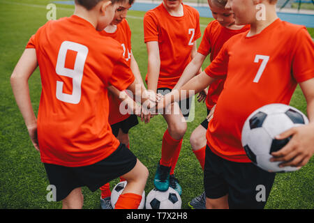 Niños de fútbol poniendo en manos del equipo. Los chicos del equipo de la Escuela de Fútbol Huddling. Los niños manos juntas en un grupito