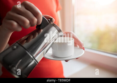 Una mujer vierte café en una taza de café. Foto de stock