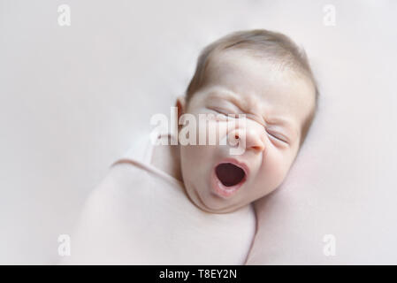 Bebé niña bostezo acostado en una rosa blancket