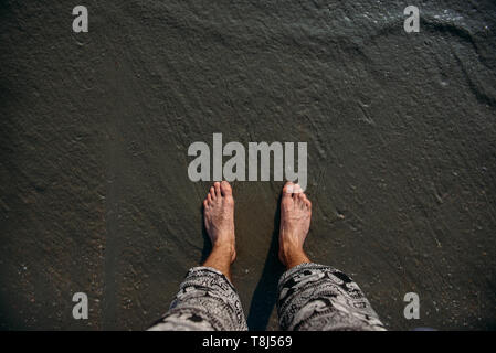 Los pies del hombre de pie en la playa, la prohibición de Ao Nang, Krabi, Tailandia