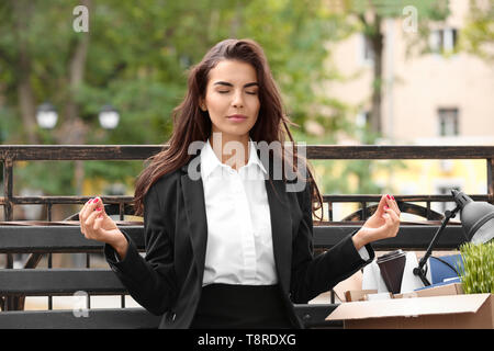Los jóvenes lanzaron mujer con cosas personales meditando en un banco al aire libre Foto de stock