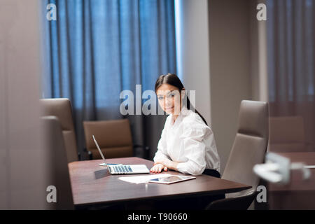 Hermosa joven empresaria usando el portátil en la sala de conferencias