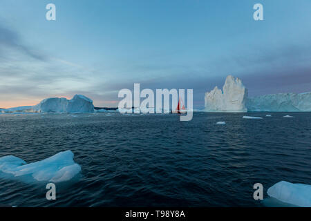 Los icebergs y velero en la bahía Disko del solsticio, Groenlandia Foto de stock