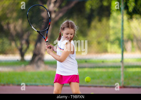 Niño jugando tenis en el tribunal interior. Niña con raqueta de tenis y la bola en un club deportivo. Ejercicio activo para los niños. Las actividades de verano para niños.