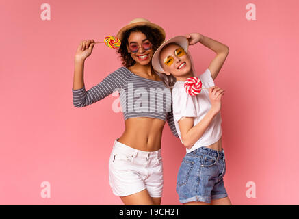 Milenario positiva mujer posando con Lollipops sobre fondo de color rosa Foto de stock