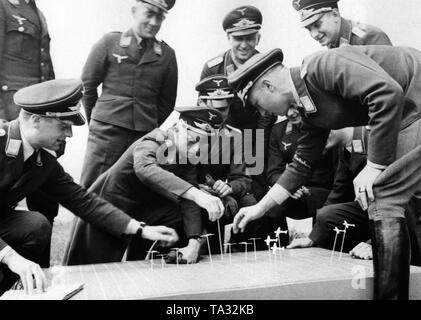Oficiales de la Luftwaffe, de que el soldado en la parte delantera derecha pertenece a la Kampfgeschwader 1 "Hindenburg" bombardero ala, practicar procedimientos tácticos en un modelo con aviones pequeños. Foto de stock