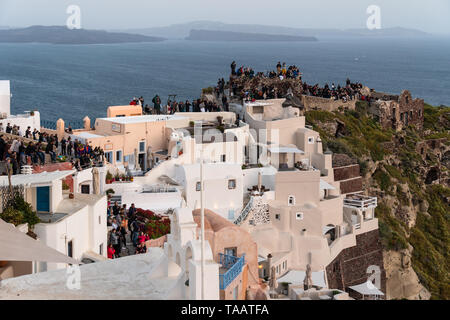 Santorini, Grecia - El 7 de mayo de 2019: una gran multitud de turistas se reúnen en el famoso mirador de Oia para comprobar la puesta de sol sobre la aldea de Santori icónico