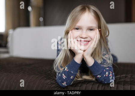 Retrato de niña sonriente con huecos entre los dientes y la cabeza entre las manos
